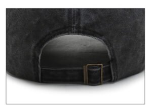 Black faded washed cotton baseball cap, vintage bronze metal buckle rear strap, adjustable opening close-up plain white backdrop