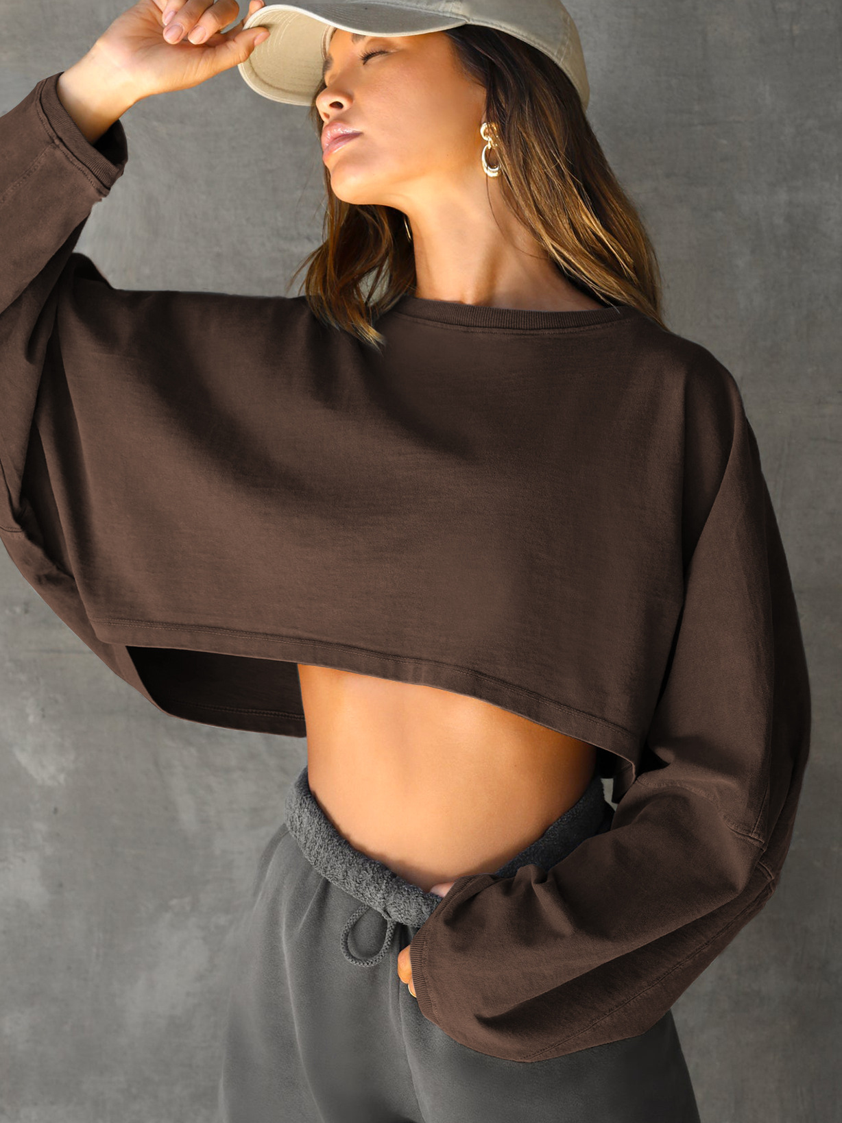 Brown Oversized Cropped Sweatshirt - Casual Loungewear View Womens brown oversized cropped long sleeve sweatshirt, loose fit with wide sleeves, paired with grey sweatpants, casual loungewear and streetwear style