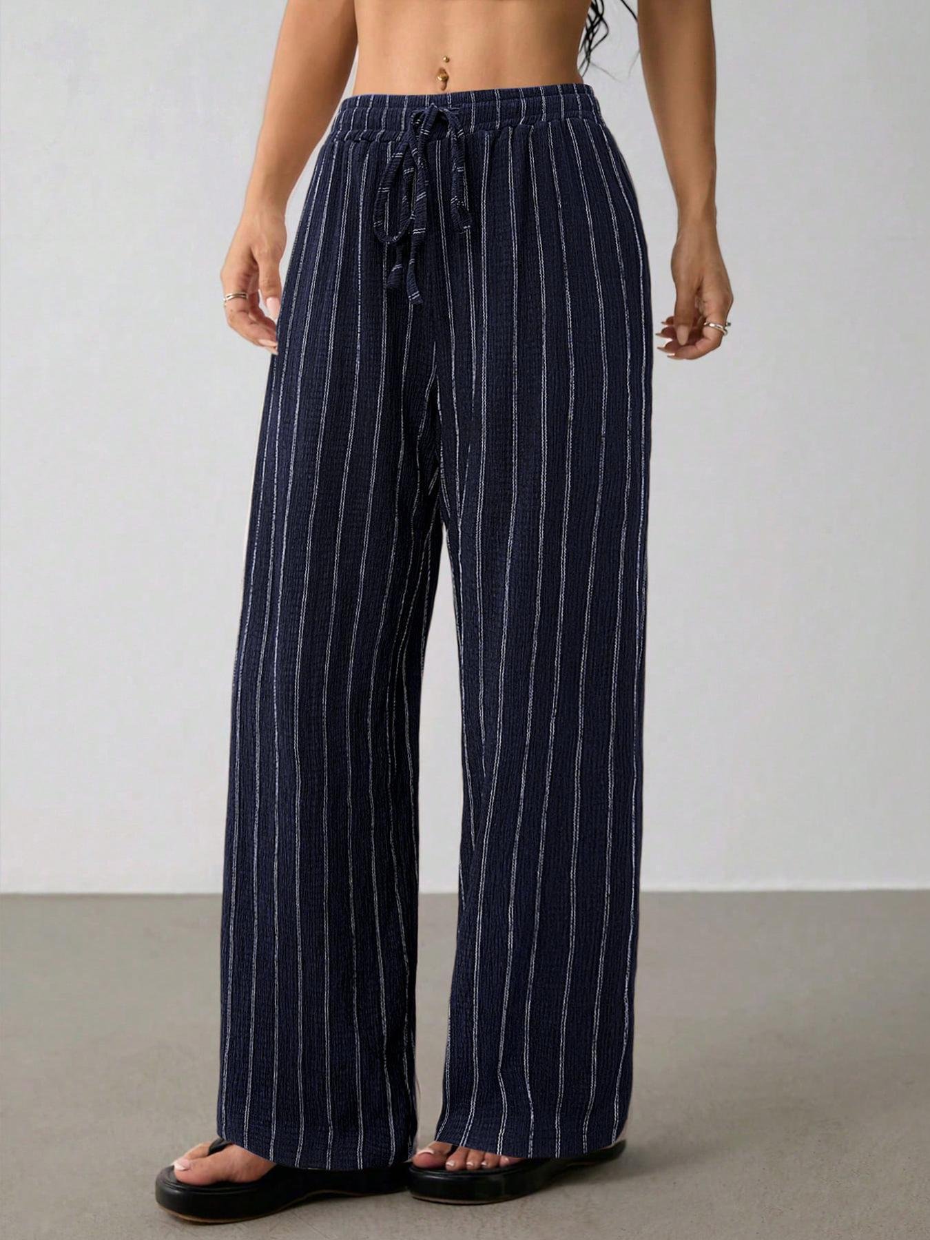 Navy Blue Striped Wide Leg Pants Loose Wide Leg Crinkle Palazzo Trousers Side angle navy vertical stripe loose wide leg trousers, stretch elastic waist, lightweight crinkle woven fabric, model with platform slide sandals indoor studio