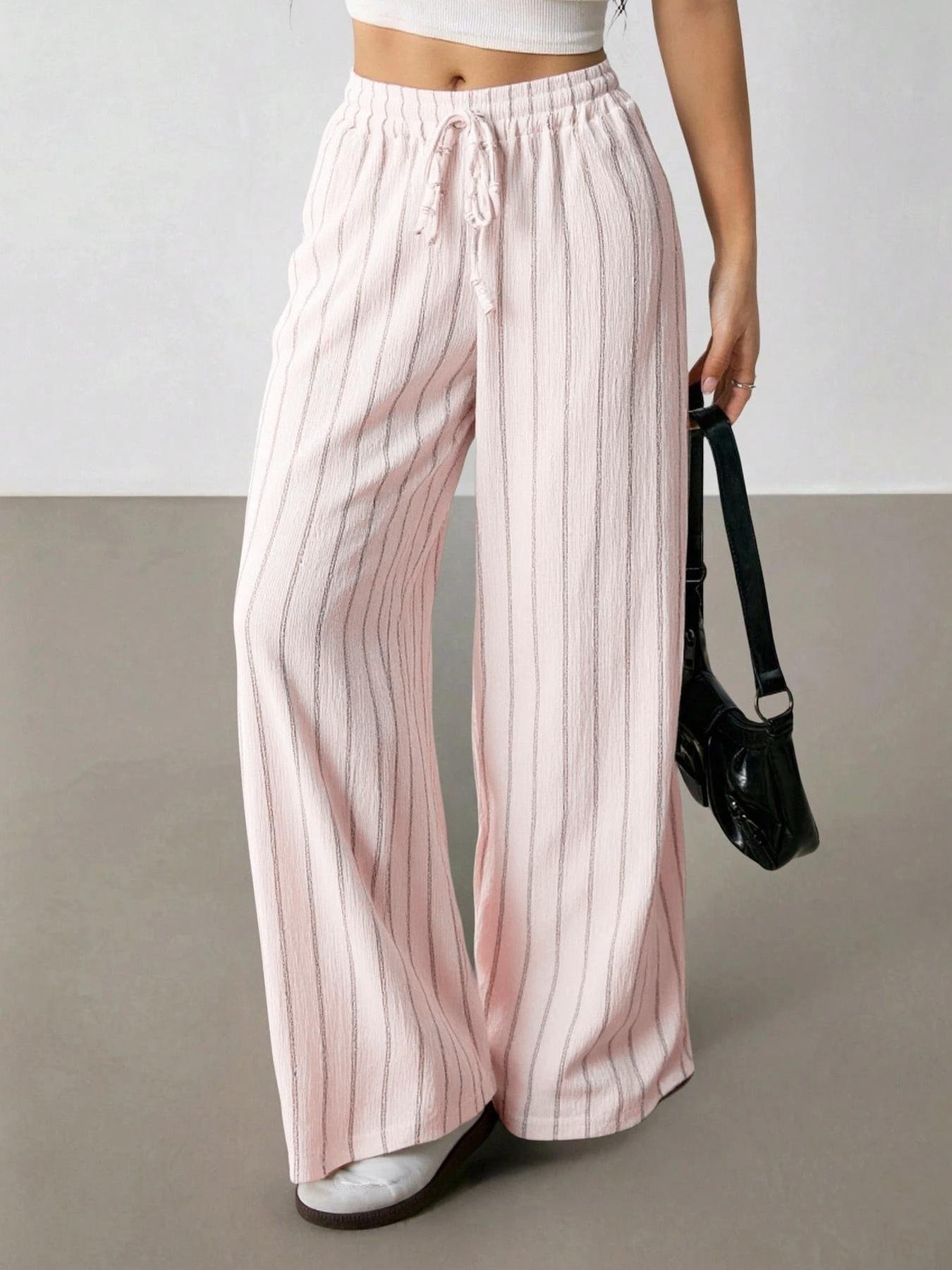Pastel Pink Striped Wide Leg Pants Crinkle Elastic Waist Casual Trousers Light pink vertical stripe flowy wide leg pants, full stretch ruffle waist, adjustable drawstring, crinkle textured fabric indoor casual fashion photo