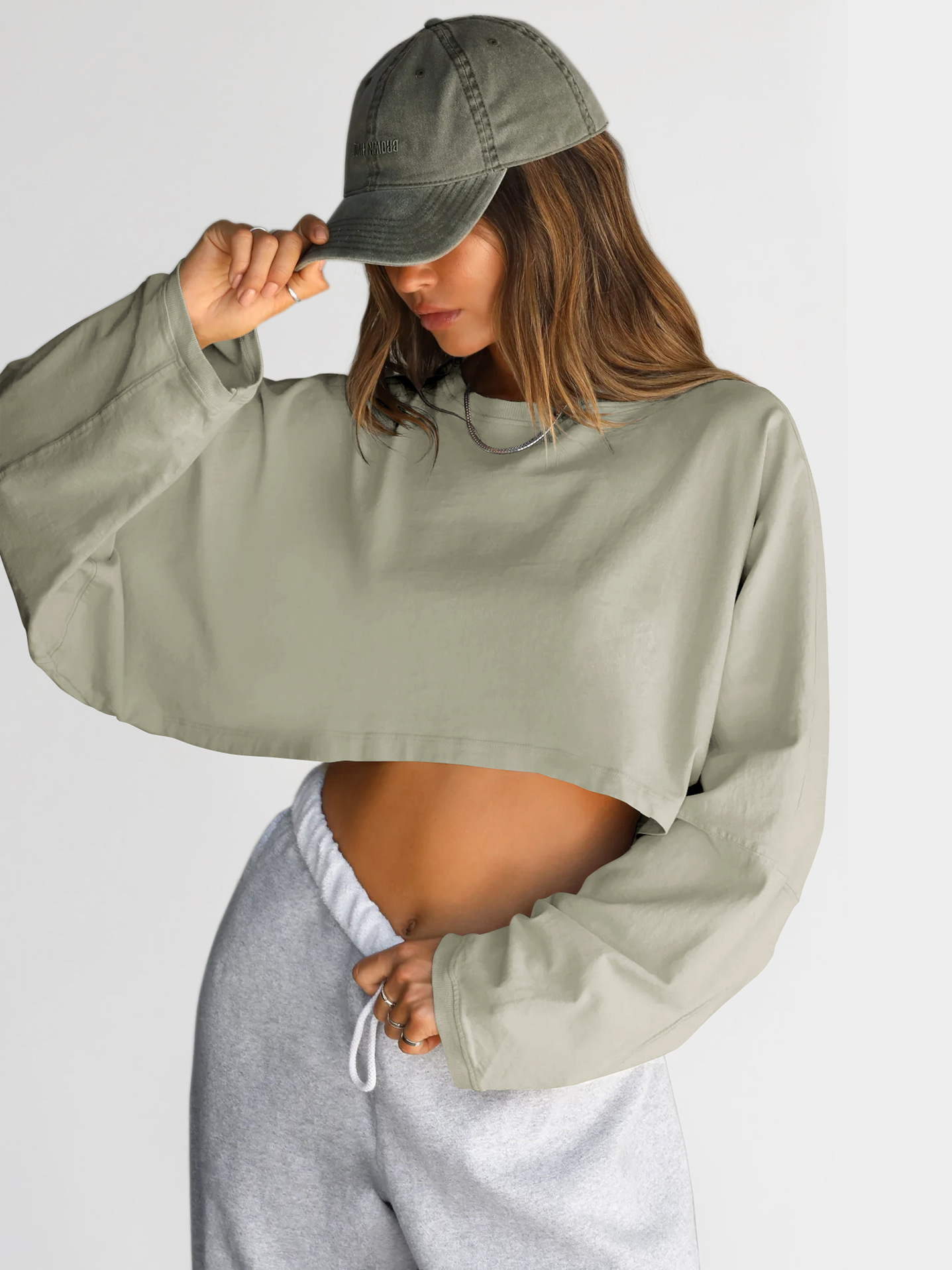 Womens light green oversized cropped long sleeve sweatshirt, vintage pigment dyed finish, loose fit with dropped shoulders, paired with grey sweatpants, front angle view Light Green Oversized Cropped Long Sleeve Sweatshirt - Front Angle View
